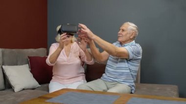 VR kulaklıklı büyükbaba ve büyükanne oyun oynuyorlar, sanal gerçeklik 3D video izliyorlar.