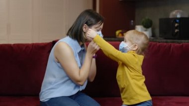 Küçük kız evde hasta annesinin koruyucu tıbbi maskesini takıyor. Coronavirus karantina kilidi