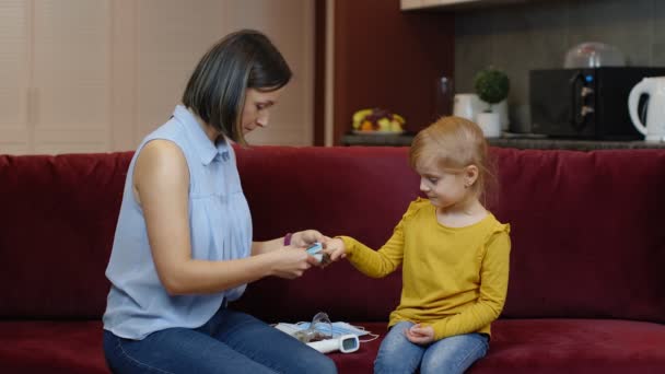 Madre midiendo, monitoreando la saturación de oxígeno con oxímetro digital de pulso de su hija en casa — Vídeos de Stock