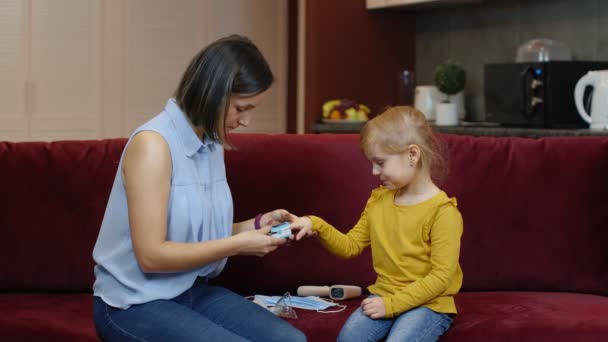 Matka měření, monitorování nasycení kyslíkem s digitálním pulzním oxymetrem své dcery doma — Stock video