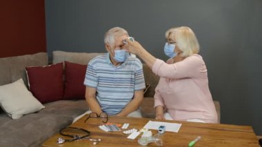 Üst düzey çiftler Coronavirus kilitlemesi sırasında temassız dijital termometreyle sıcaklık ölçer.