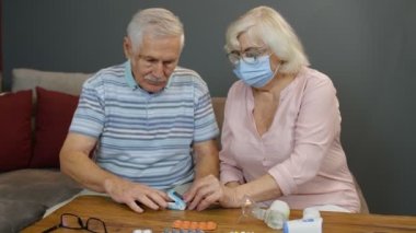 Yaşlı çift büyükbaba ve büyükanne dijital nabız oksimetresiyle oksijen doygunluğunu izliyorlar.