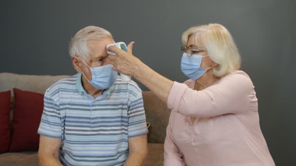 Üst düzey çiftler Coronavirus kilitlemesi sırasında temassız dijital termometreyle sıcaklık ölçer. — Stok video