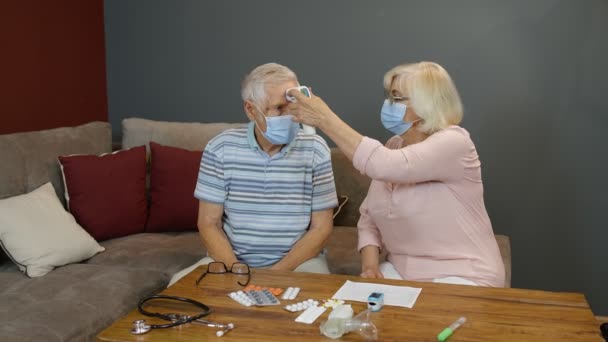 Senior par mäter temperatur med kontaktlös digital termometer under coronavirus lockdown — Stockvideo