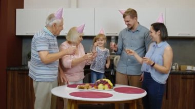 Çocuklu çoklu aile üyeleri doğum günü partisini kutluyorlar. Şampanya içiyor.