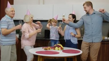 Çocuklu çoklu aile üyeleri doğum günü partisini kutluyorlar. Şampanya içiyor.