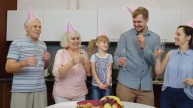 Çocuklu çoklu aile üyeleri doğum günü partisini kutluyorlar. Şampanya içiyor.
