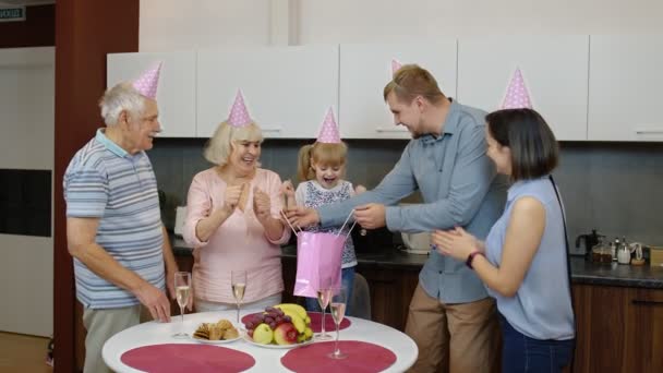 Mutter, Vater und Großeltern überreichen Geschenktüte für das kleine Mädchen. Geburtstag feiern — Stockvideo