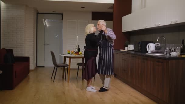 Pareja mayor enamorada bailando. Cena romántica con vino y velas celebrando aniversario — Vídeo de stock