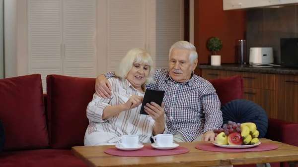 Abuelos mayores pareja hablando y usando tableta digital en casa. Bloqueo del Coronavirus — Foto de Stock