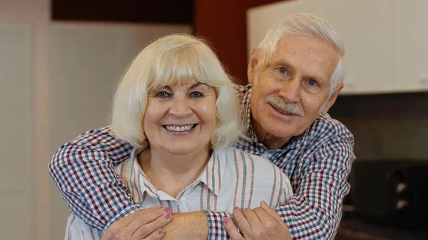 Starsza rodzina przytula się, śmieje, uśmiecha patrząc w kamerę podczas zamknięcia koronawirusu — Zdjęcie stockowe