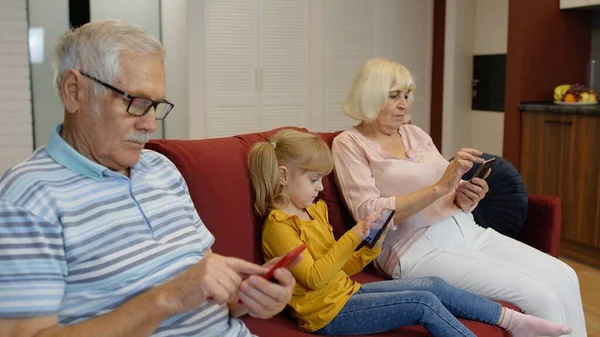 Abuelos de pareja mayor con nieta niña usando tableta digital, teléfono móvil —  Fotos de Stock