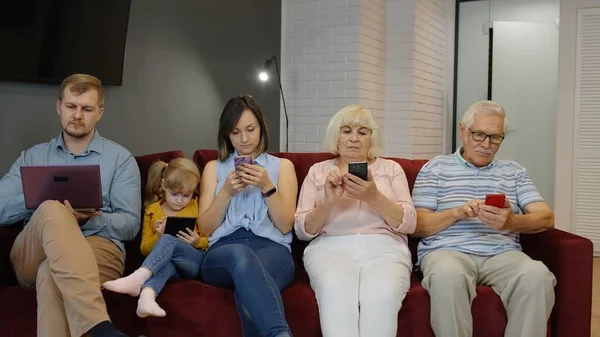 Adicta a la familia gadgets utilizando el teléfono móvil, tableta, portátil ignorándose mutuamente en casa. Obsesión —  Fotos de Stock