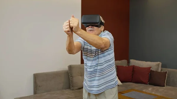 Senior grandfather man in virtual headset glasses watching amazing 3D video in 360 vr helmet at home
