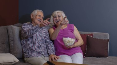 Neşeli yaşlı çift futbol fanatikleri spor televizyon izleyip futbol takımını kazanıyor.