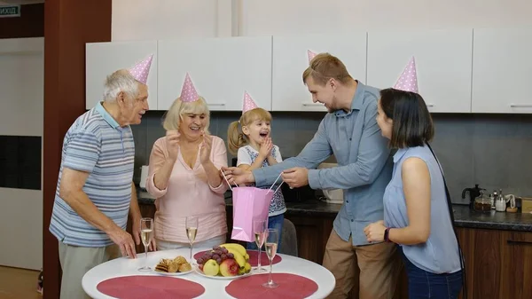 Mãe, pai e avós dando saco de presente para menina. Celebrando aniversário de aniversário — Fotografia de Stock