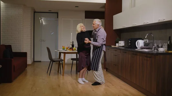 Senior couple in love dancing. Romantic evening supper with wine and candles celebrating anniversary