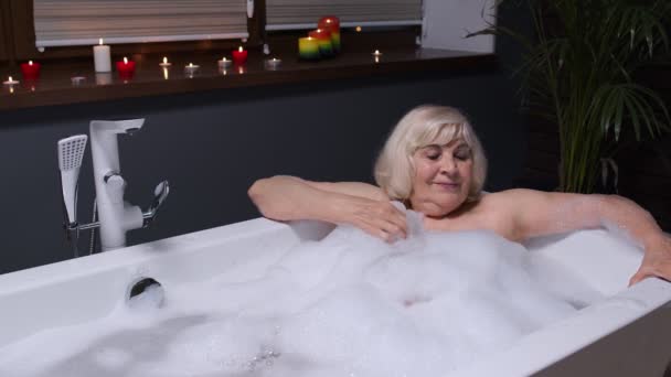 Belle femme âgée active couchée dans un bain chaud avec des bulles, profitant de la détente. Personnes âgées — Video