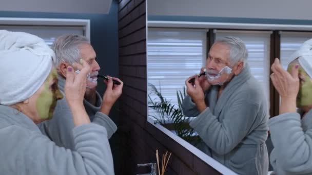 Büyük anne yüz maskesi takıyor ve büyükbaba banyoda tıraş oluyor. — Stok video
