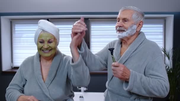 Senior couple homme et femme en peignoir dansent dans la salle de bain en s'amusant profiter du temps libre — Video