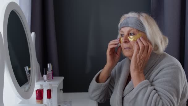 Anciana abuela anciana cuidando la piel cerca de los ojos y las arrugas, maquillándose en casa — Vídeos de Stock