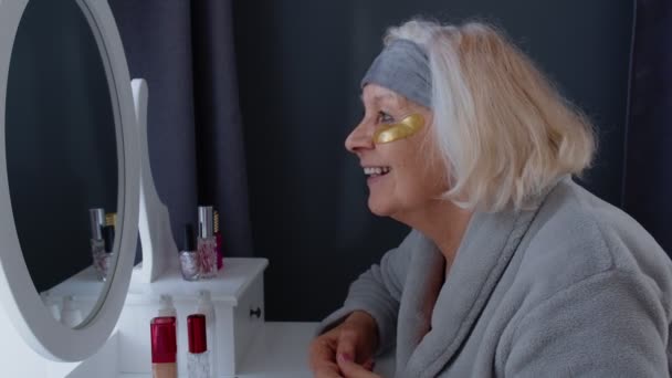 Стара бабуся похилого віку наносить проти зморшок очей, наносить макіяж вдома — стокове відео