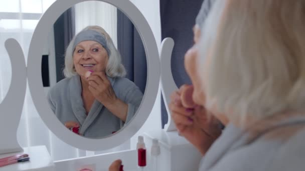 Stara babka starsza opiekuje się skórą, nakłada podkład przeciwzmarszczkowy gąbką — Wideo stockowe
