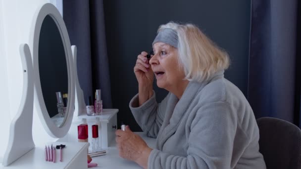 Abuela anciana anciana que aplica rímel de pestañas, se maquilla, cuida la piel — Vídeo de stock
