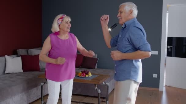 Gelukkig oud senior paar dansen het hebben van plezier vieren pensionering verjaardag in woonkamer thuis — Stockvideo