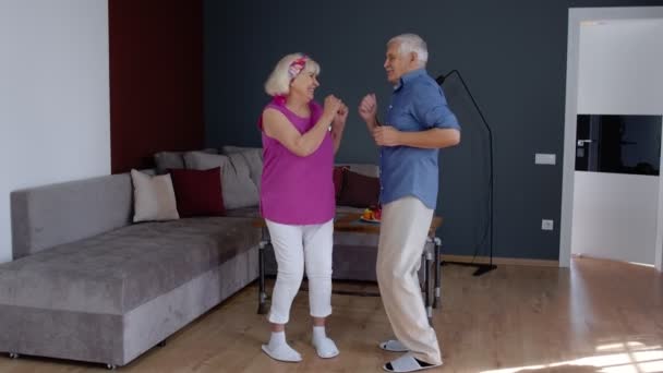 Szczęśliwy stary senior para taniec zabawy świętowanie rocznicy przejścia na emeryturę w salonie w domu — Wideo stockowe