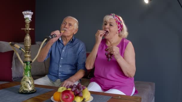 Stylowa para seniorów cieszyć się palenia hookah, jedzenie owoców w domu, świętowanie, zabawy razem — Wideo stockowe