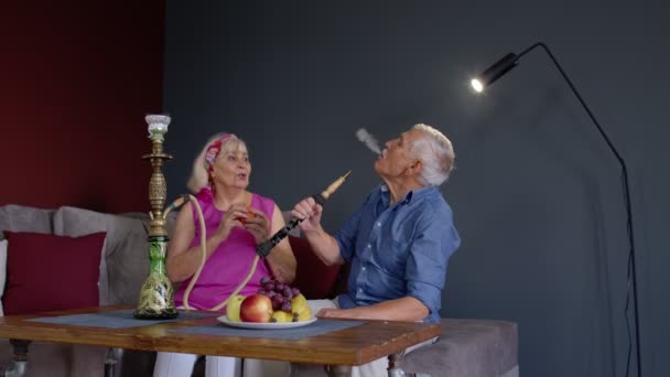 Starsza para palenie hookah jedzenie owoców świętowanie rocznicy przejścia na emeryturę w salonie w domu — Wideo stockowe