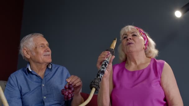 Pasangan kakek nenek senior stylish menikmati hookah merokok di rumah, merayakan, bersenang-senang bersama — Stok Video