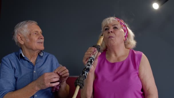 Pasangan senior merokok hookah makan buah-buahan merayakan ulang tahun pensiun di ruang tamu di rumah — Stok Video