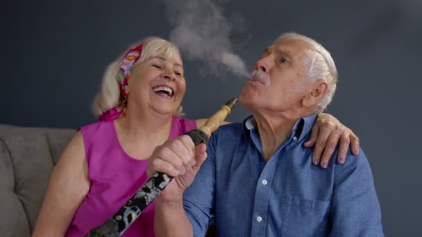 Pareja mayor fumando narguile en casa. Abuela y abuelo mayores divertirse, relajarse — Vídeo de stock