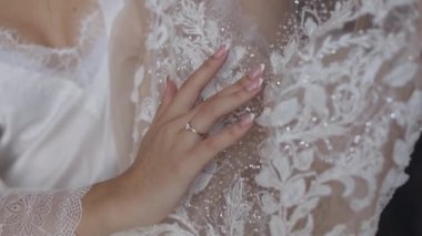 Beyaz ipek elbiseli gelin gelinliğine dokunuyor. Sabah hazırlıkları. Yavaş çekim