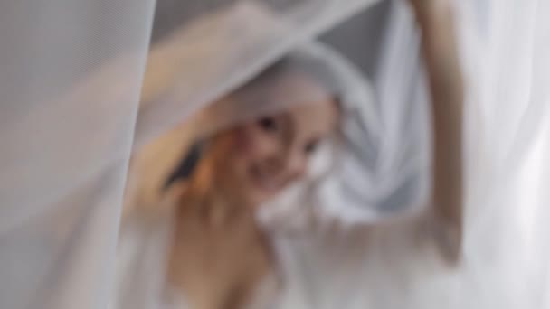 Noiva em vestido de boudoir abaixo do véu e em uma veste de seda. Preparativos da manhã de casamento antes da cerimônia — Vídeo de Stock