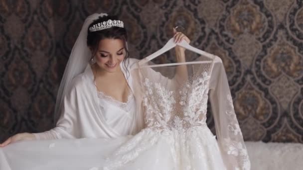 Невеста в нижнем белье крутится в танце со своим свадебным платьем. Белое будуарное платье и вуаль — стоковое видео