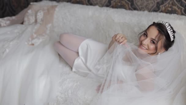 Sposa in abito boudoir bianco, velo e vestaglia di seta. Preparativi del mattino di nozze prima della cerimonia — Video Stock