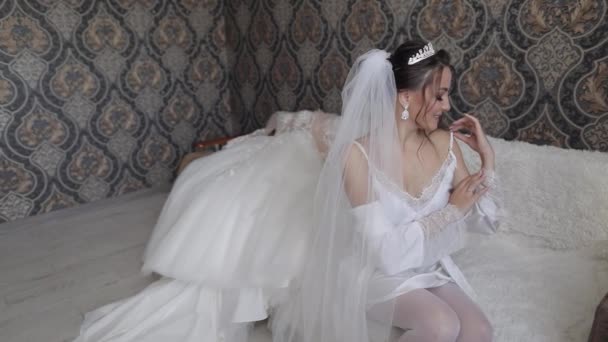 Novia en vestido de tocador blanco, velo y túnica de seda. Preparativos de boda mañana antes de la ceremonia — Vídeos de Stock