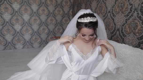 Novia en vestido de tocador blanco, velo y túnica de seda. Preparativos de boda mañana antes de la ceremonia — Vídeos de Stock