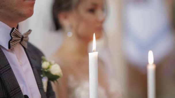 Recién casados. Caucásico novia y el novio de pie en la iglesia con velas en la ceremonia de la boda — Vídeos de Stock