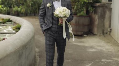 Damat, elinde düğün buketiyle çalıların arasından sevgili gelinine doğru gidiyor.