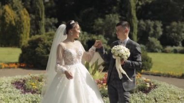 Yeni evliler. Gelin ile beyaz damat parkta yürüyor, sarılıyor, sarılıyor. Düğün çifti