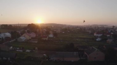 Hava aracı güneş doğarken eski köyü görüyor. Kuşlar büyük sürüler halinde uçar.