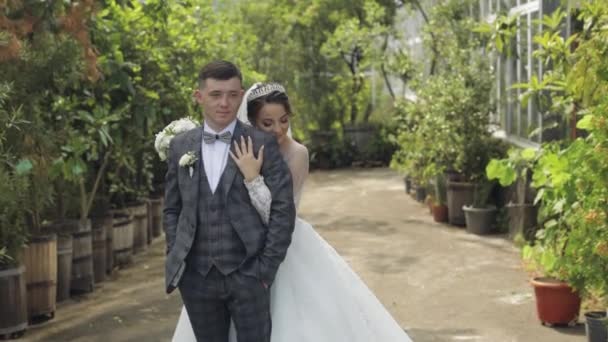 Les jeunes mariés. marié caucasien avec mariée marchant, embrassant, câlins dans le parc. Couple de mariage — Video