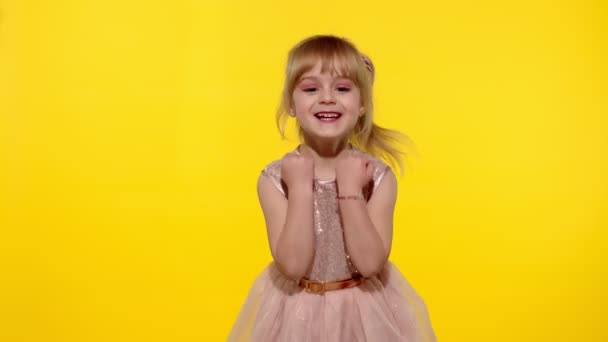 Bonjour ou au revoir. Petite fille enfant blonde souriante saluant avec la main sur fond jaune — Video