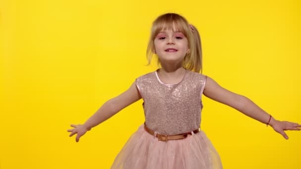 Küçük sarışın kız 5-6 yaşlarında uçuyor, dans ediyor, sarı stüdyoda kutlama yapıyor. — Stok video