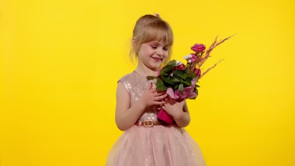 Menina pequena com maquiagem de moda de pé com buquê de flores isoladas no fundo amarelo — Vídeo de Stock