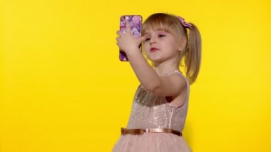 Akıllı telefon kullanan bir kız çocuğu. Sarışın çocuğun portresi cep telefonunda özçekim yapıyor.